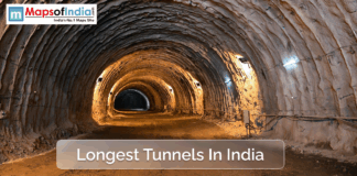 Longest Tunnels in India A view inside a large, illuminated tunnel in India, showcasing rough rock walls and ceiling with construction lights, representing one of the country's longest tunnels.
