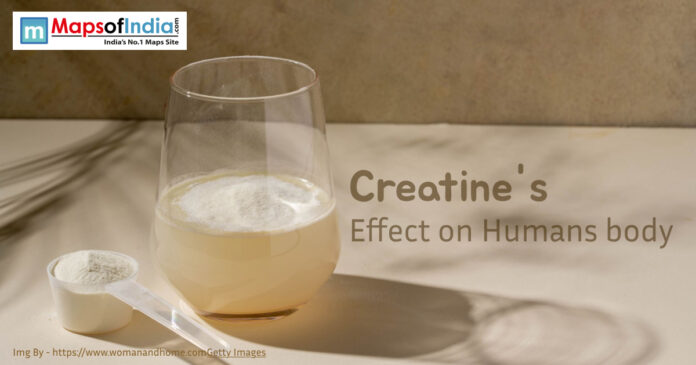 A glass of creatine mixed with water placed on a light surface beside a scoop of creatine powder.
