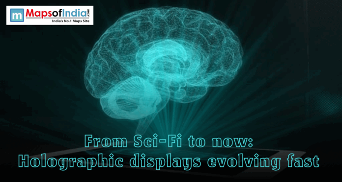 A glowing blue 3D holographic brain projection emerging from a flat surface, with the headline "From Sci-Fi to now: Holographic displays evolving fast"