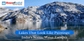 Lakes That Look Like Paintings: India’s Scenic Water Escapes Snow-covered mountains reflecting in a serene blue lake in India, showcasing a picturesque landscape under clear skies, titled “Lakes That Look Like Paintings.”