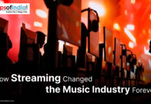 How Streaming Changed the Music Industry Forever Rows of people using desktop computers with large monitors and headphones, set against a vibrant orange and red background, illustrating the concept of streaming’s impact on the music industry.