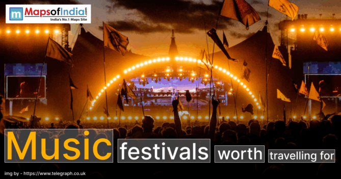 A large outdoor music festival at sunset with a crowd of people holding flags, facing a brightly lit stage with an illuminated arch and Screens, creating a vibrant concert atmosphere.