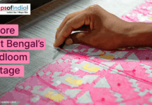 Explore West Bengal’s Handloom Heritage A close-up of a hand weaving a colorful pink and yellow handloom textile, promoting West Bengal’s handloom heritage.