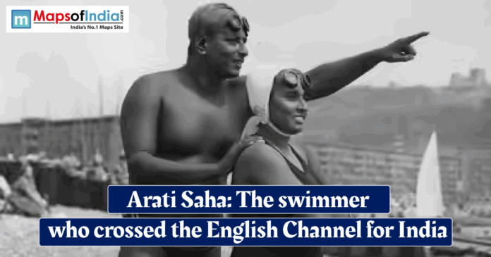 Arati saha Historic black‑and‑white photo of Indian swimmer Arati Saha in a swimsuit on a beach, guided by a man pointing toward the sea, with overlaid text reading “Arati Saha: The swimmer who crossed the English Channel for India.”