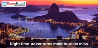 Night Time Adventures Most Tourists Miss A vibrant coastal city at dusk with glowing lights, mountains, and a calm bay, illustrating night-time adventures most tourists miss.