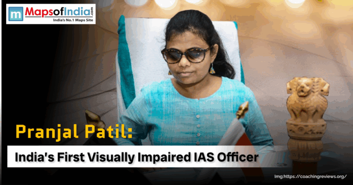 Pranjal Patil, India's first visually impaired IAS officer, sits at her desk with a small Indian flag and the Ashoka Pillar emblem.