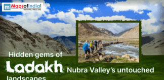 Unexplored Treasures of Ladakh: Nubra Valley’s Virgin Landscapes Hikers crossing a rocky stream in Ladakh’s Nubra Valley, surrounded by rugged mountains and green landscapes under a bright sky.
