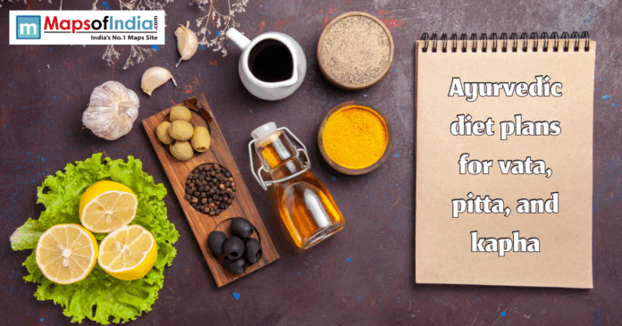 Flat lay of Ayurvedic foods and spices including lemons, lettuce, garlic, olives, oil, turmeric, and pepper beside a notebook reading “Ayurvedic diet plans for vata, pitta, and kapha.”