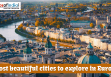 Most Beautiful Cities To Explore In Europe An aerial view of the historic city of Salzburg, Austria, featuring the Salzach River winding through colorful buildings and prominent domed cathedrals under a warm sunset glow. A text overlay at the bottom reads, "Most beautiful cities to explore in Europe."