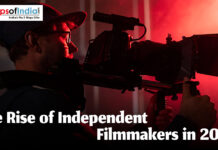 The Rise of Independent Filmmakers in 2026 A filmmaker in a baseball cap operating a professional cinema camera in a dark room with dramatic red lighting, featuring the text "The Rise of Independent Filmmakers in 2026."