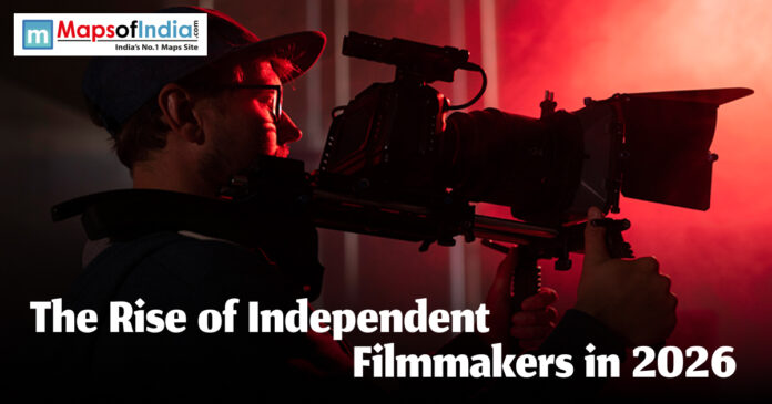 Rise of independent A filmmaker in a baseball cap operating a professional cinema camera in a dark room with dramatic red lighting, featuring the text "The Rise of Independent Filmmakers in 2026."