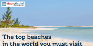 Top Beaches In The World You Must Visit A serene tropical beach with white sand, turquoise water, and a thatched umbrella under a clear blue sky. The text "The top beaches in the world you must visit" is at the bottom, with a "MapsOfIndia" logo in the top left.
