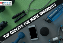 Top Gadgets for Home Workouts Top-down view of fitness equipment including dumbbells, a jump rope, resistance bands, a smartphone, and water bottles on a green and grey gym mat with the text "TOP GADGETS FOR HOME WORKOUTS."
