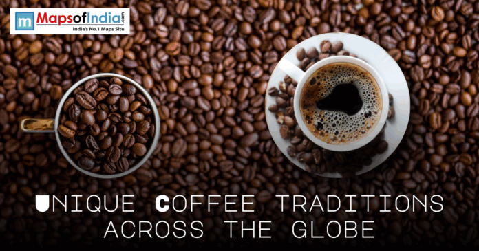 Top-down view of a cup of freshly brewed coffee and a mug filled with roasted coffee beans on a background of scattered beans, with text reading “Unique Coffee Traditions Across the Globe,” branded by MapsofIndia.com.