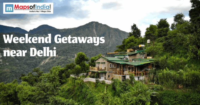 Scenic mountain landscape with a stone cottage, green hills, and 'Weekend Getaways near Delhi' text. Maps of India logo visible.