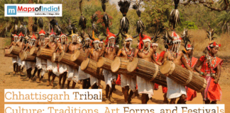 Chhattisgarh Tribal Culture: Traditions, Art Forms, and Festivals Tribal men in traditional attire performing a cultural dance with large drums during a festival procession in Chhattisgarh, wearing ornate headgear and bead jewelry, with banner text reading “Chhattisgarh Tribal Culture: Traditions, Art Forms, and Festivals.”