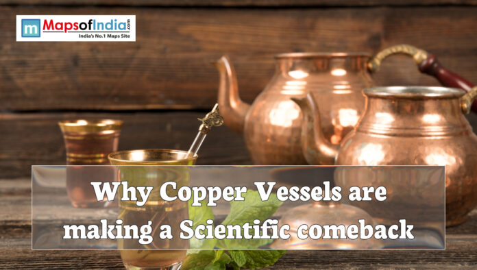 Copper vessels including a jug, pot, and glass placed on a wooden table with the text “Why Copper Vessels are making a Scientific comeback” displayed over the image