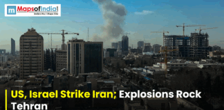 US, Israel Strike Iran; Explosions Rock Tehran Smoke rising over Tehran’s skyline with high-rise buildings and construction cranes, overlaid with the headline “US, Israel Strike Iran, Explosions Rock Tehran” and a Maps of India logo