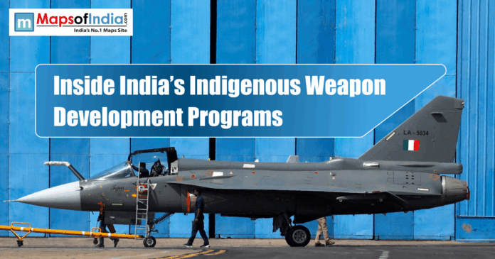 Indian Tejas fighter jet displayed in front of a blue hangar with the title “Inside India’s Indigenous Weapon Development Programs.”