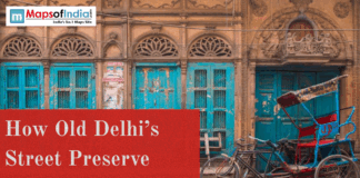 How Old Delhi’s Street Preserve Centuries of History Historic Old Delhi street with carved arches, turquoise wooden doors, and a parked cycle rickshaw in front of a heritage building.