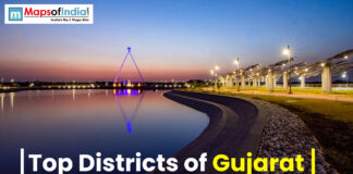 Top Districts of Gujarat Scenic waterfront view in Gujarat at sunset with illuminated walkway and modern architectural structure, showcasing urban development